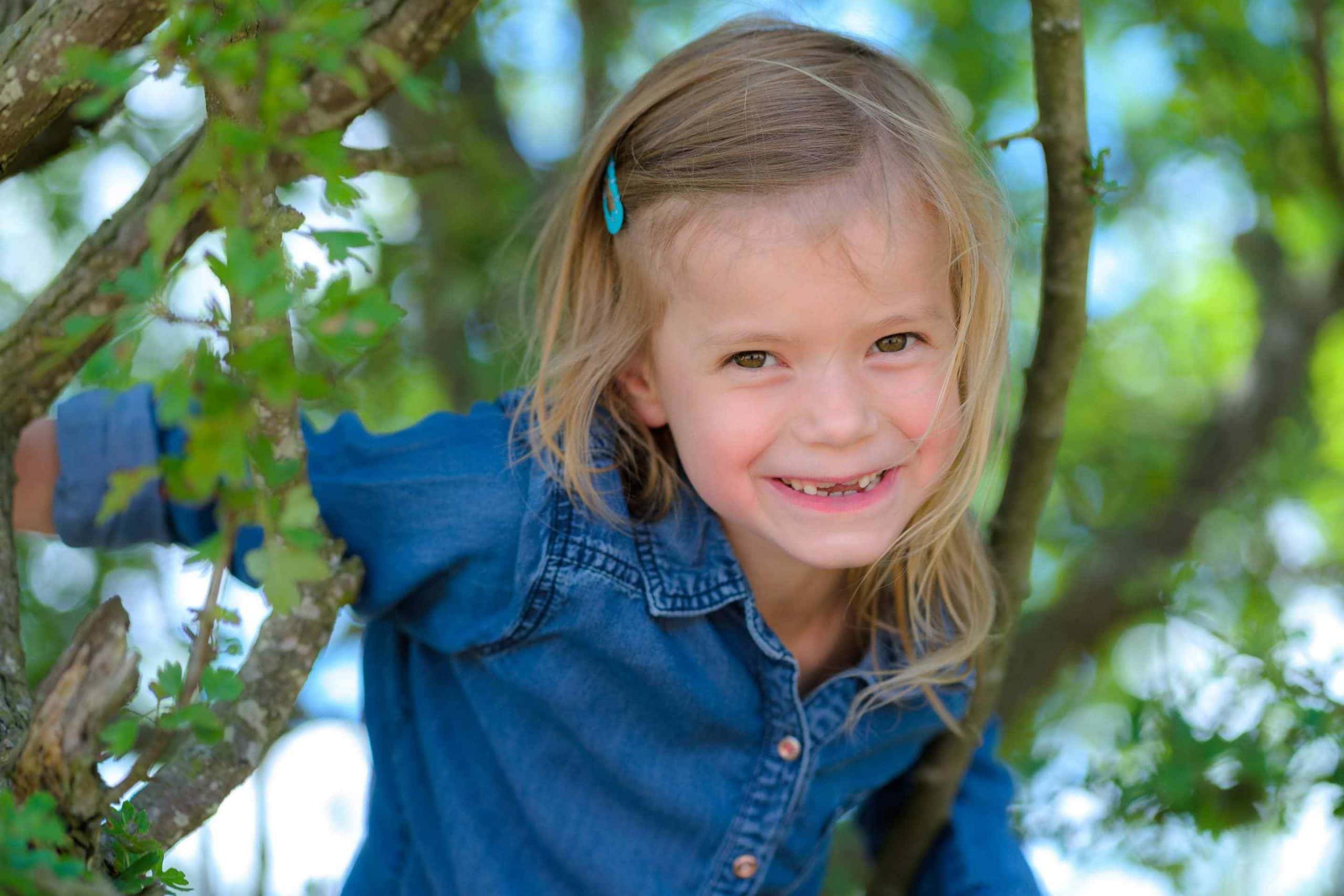Kinderfotografie portret tussen bomen meisje door kinderfotograaf Grietje Mesman